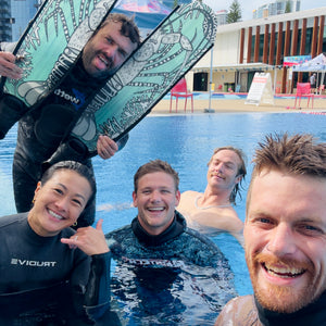 Group of people smiling in pool with diving fins